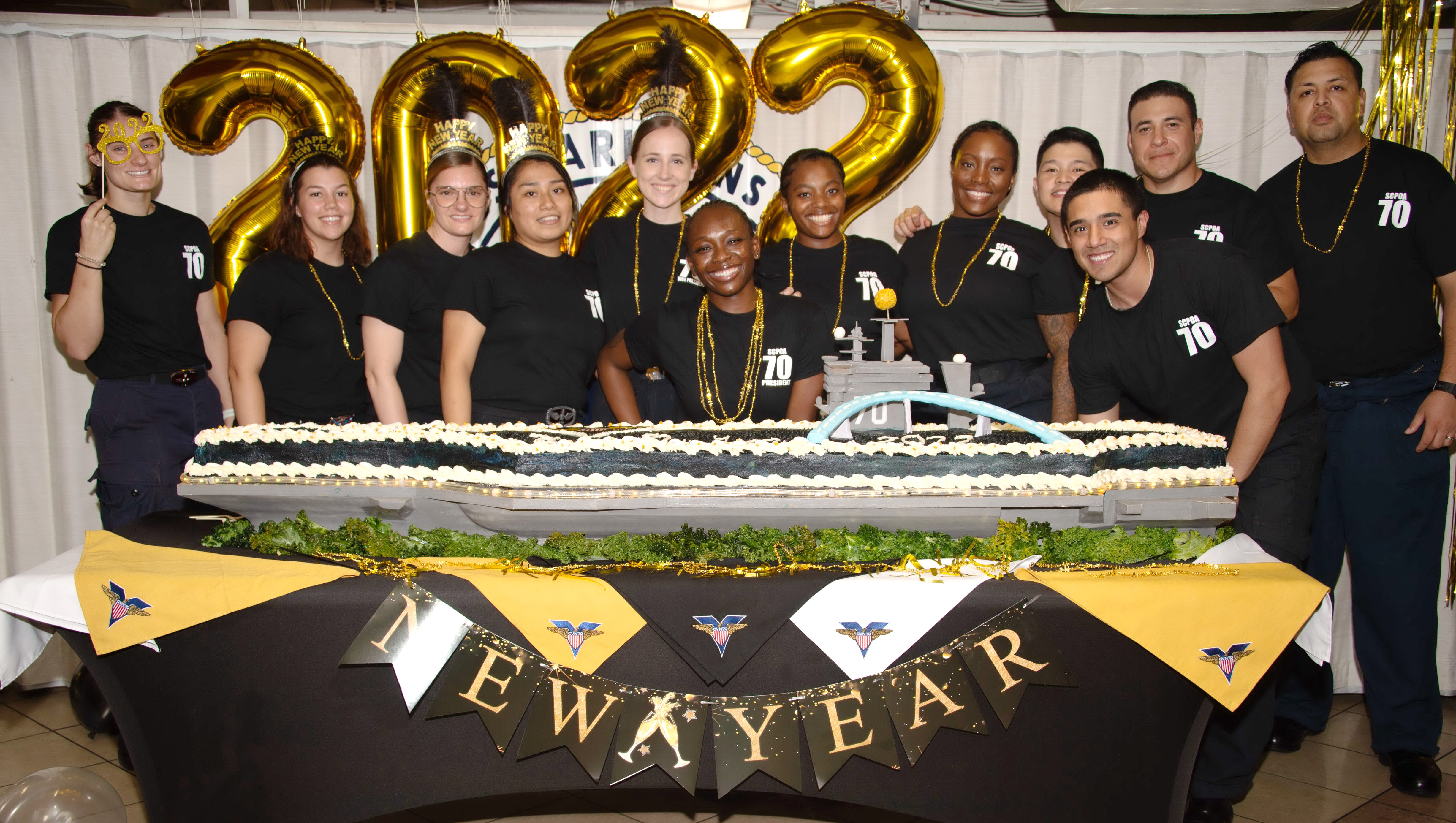 USS Carl Vinson (CVN 70), pose next to a cake in the mess deck during a New Year’s Eve event, Dec. 31, 2021.JPG